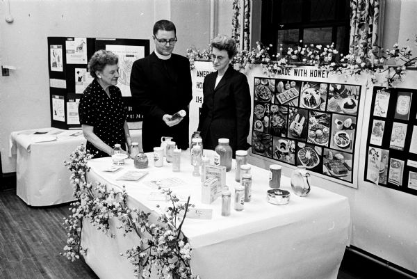 Marjorie Slothower, 305 Norris Court, left, and Gretchen Sienering, 114 West Gilman Street, speaking with Reverend Paul Hoornstra, pastor of Grace Episcopal Church, 6 North Carroll Street. A display of commercial products was one of the featured booths at the Harvest Festival at the church.