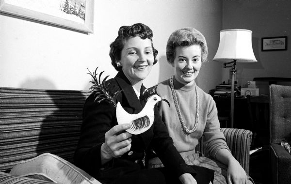 The Junior Division of the University League holding a holiday cocktail party and dance at the Madison Club. Shown displaying one of the decorations are (L-R) Mrs. Albert Grover, 27-F University Houses, chairman of the dance planning committee; and Mrs. Raymond Ralph, 27-C University Houses, member of the decorating committee.