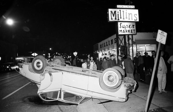 The overturned car in front of Millins Supermarket on Monroe Street belonged to William Matthias. He hit a lamppost and flipped the car while trying to avoid a bandit fleeing in a police chase.