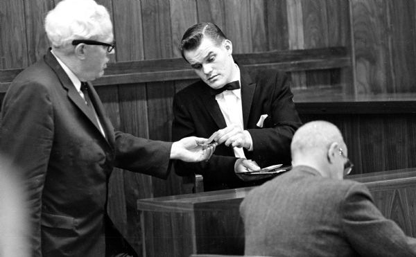 William Welter demonstrates for his attorney, Vaughn Conway, how he handed his driver's license to Policeman James Jantz before the shooting started. William Welter Jr., Lawrence Nutley, and Richard Nickl, all of the Chicago area, were accused of slaying Patrolman James Lantz, Baraboo, and wounding Lake Delton Police Chief Eaugene Lee Kohl in an early morning gun battle in front of the Lake Delton village hall.