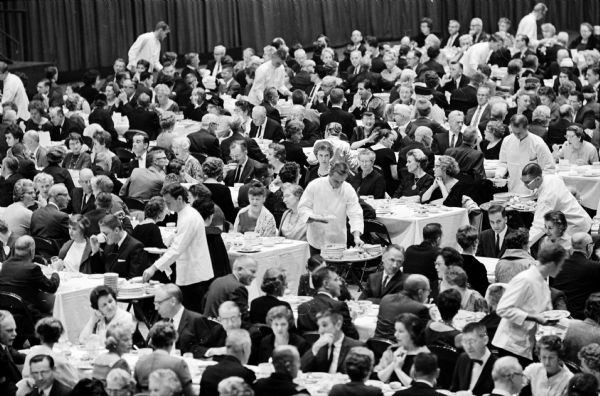 The Inaugural Banquet for the newly inaugurated President of the University of Wisconsin, Fred H. Harrington, was held at the Field House. Operating with scientific precision with instructions coming from a control tower in the balcony, a crew of about 100 waiters served 1500 dinners in ten minutes. The control tower was operated by Douglas Osterheld, associate director of the Memorial Union. Field telephones, walkie talkies, binoculars and flashing lights were used to signal the waiters.