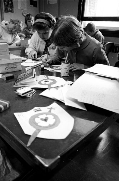A group of children drawing designs onto paper shields.