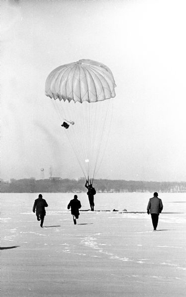 Three U.W. students, Marty Christensen, Robert Falconer and Gary Schroeder, jumped out of an airplane over ice-covered Lake Mendota to advertise the political campaign of Dwayne "Admiral Dewey" Norris who is running for Military Ball King at the University of Wisconsin. The Military Ball King will be chosen at the Ball.