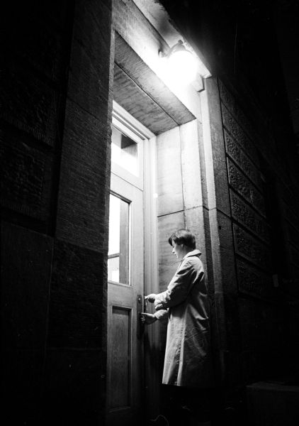 Mary Captaine, a junior at the University of Wisconsin, from Appleton, letting herself into Barnard Hall with her key late at night. This dormitory is under a pilot study on freer hours for women students.