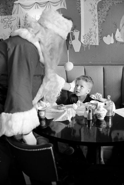 Unidentified youngster shown enjoying breakfast with Santa at Manchester's Department Store.