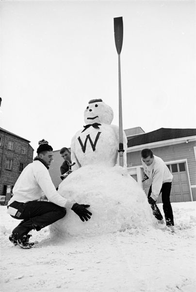 Members of the U.W. crew build a snowman prior to their departure with their coach, Norm Sonju, for a rowing event in Winter Park, Florida. Shown (L-R) are rowers Chuck Ruedebusch, Kansas City, Kans.; Tom Olson, Madison; and coxswain Dan Schwoerer, New Holstein, WI.