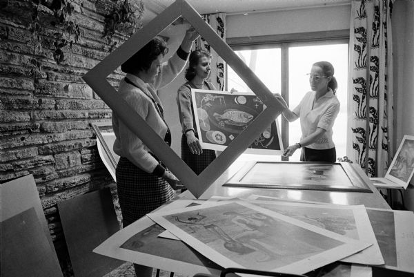 Members of the arts study group of the Monona American Association of University Women have undertaken the framing of pictures to be rented to the public through the Monona Public Library. At work (L to R) Harriet Steil, Rose Diestler and Patricia Vogel.
