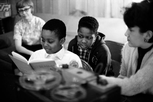 U.W. student volunteer Susan Meltzer (right) is shown helping Tony Davis (11) and John James (11) improve their reading skills. John is looking over Tony's shoulder. On the left is Susan Cook, coordinator of the program.