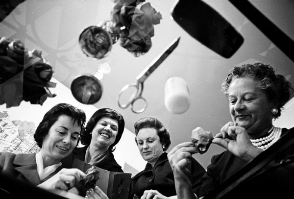 An unusual photograph of four Madison women working on decorations for the soiree of the Civic Opera Guild, taken through a glass-topped table. They are: Lorna Holmes, Arlene Houseman, Esther Suckle, and Katherine Maurer.