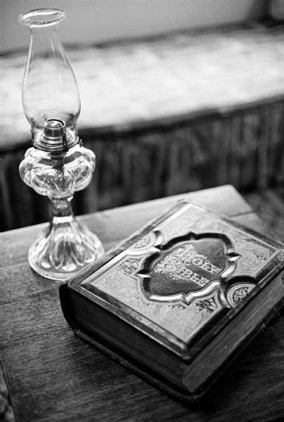 A kerosene lamp standing beside an old family Bible on a table in the antique-filled Harry Lichte home, 5314 Flad Avenue.