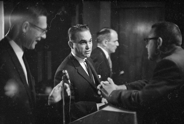Alabama governor George Wallace shaking hands with members of the Madison Exchange club. They invited Wallace to give a speech at the Cuba Club restaurant for 180 of their members. Wallace and his contention that the pending civil rights bill will "destroy the constitutional rights of everybody" were met with applause.