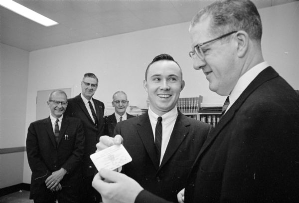 Judge William L. Buenzil, right, presents a final "report card" to Stephen Eisle who is the one thousandth graduate of the Dane County traffic school. Persons convicted of traffic violations worth three or more points may attend the school voluntarily. Others involved in presenting the classes are, left to right, Judge  Ervin Bruner; Norman Mitby, Madison Vocational, Technical, and Adult Schools director; and Lewis W. Amborn, county probation officer.