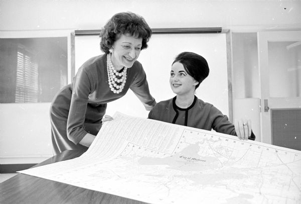 Two women employees of the Madison Chamber of Commerce office inspecting a newly published map of Madison. They are Beverly Robinson (left) administrative secretary, and Judy Fritschler (right).