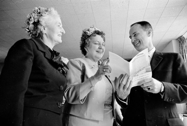 Looking on at left is alumna honoree, Isabel Craig, of Janesville, who received the Wisconsin Alumni Assn.'s distinguished service award for outstanding alumni club activities. Constance Elvehjem, chairwoman of Women's Day, and University Vice-Pres is in the center, and Robert Clodius (right), who is holding an open pamphlet, discuss the five planned seminars on the Women's Day program.  