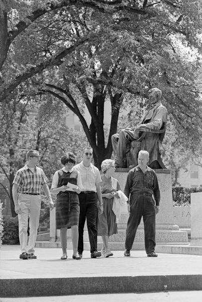 John Frederick, who will receive his doctorate from the University of Wisconsin, is showing his family around the campus. They are, left to right, his sister, Sue, his brother Kenneth and his parents, Mr. and Mrs. Orlan Frederick of Smithville, West Virginia. they are walking past the Lincoln statue on Bascom Hill.