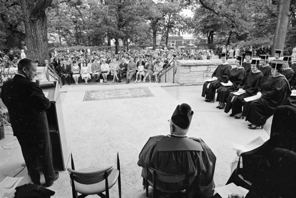 Angus Rothwell, state superintendent of public instruction, speaking to the graduating class of Edgewood College. Bishop William P. O'Connor is present on the stage.