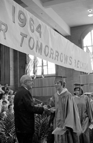 Glenn W. Stephens, Madison School District Board of Education President, awarding a diploma to a graduate at the East High School graduation ceremony.