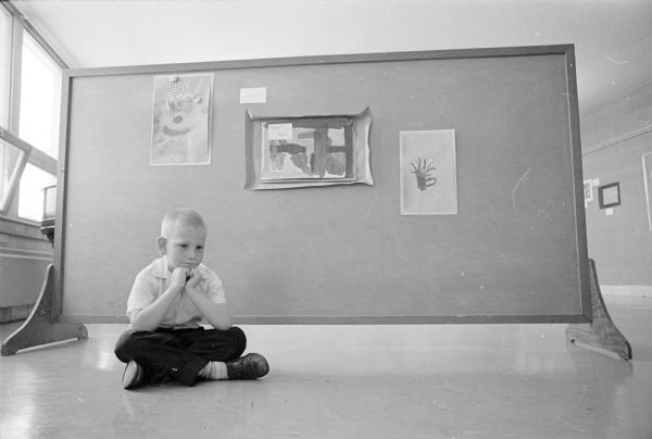 Ralph Webb, 6, sitting on the floor in front of three of his works of art on display at the First Baptist Church Children's Day art exhibit.  Ralph's art works were among the approximately 50 works of children from nursery classes through sixth grade on display in the church library and an adjoining room.