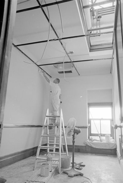 A painter is working on a wall in the State Capitol during the process of redecorating. Over a four-year period that started in 1961 the state Building Commission has spent a total of $1.2 million for converting the Capitol's electrical system from direct current to alternating current.