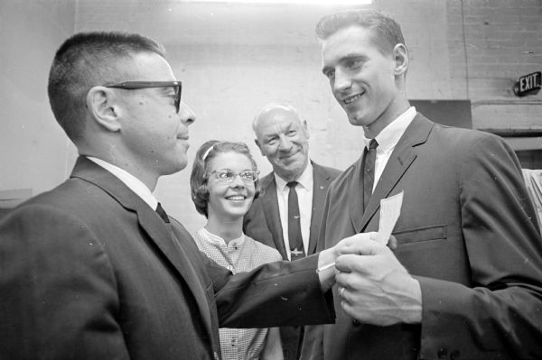 David Tymus (right) is presented the Arthur J. Sweet Memorial scholarship by the company president Sheldon Sweet. The scholarship recipient is selected by the University of Wisconsin dean of students, dean of men, and the varsity baseball coach. Looking on are David's wife, Sally, and baseball coach Arthur (Dynie) Mansfield.