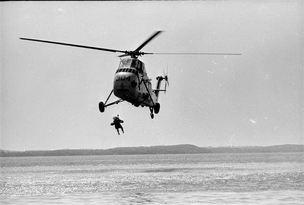 Truax Field pilots practicing water survival techniques in Lake Mendota near Warner Beach. The pilots, members of the 325 Fighter Interceptor Squadron, were hooked to a chair-like harness, dropped into the water and pulled backwards through the water by a speedboat to simulate the drag of an open parachute. Pilots were picked up by helicopters.  The training is part of an overall Air Force program to improve survival of pilots when they parachute into open water. It is good training for the kind of conditions encountered in the Vietnam area.