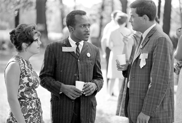 The original caption states: "Willie Peacock, Charleston, Mississippi, field secretary for Student Non-Violent Coordinating Commission, discussing the Summer Project with Dr. Peter Weiss, University of Wisconsin psychologist, right, as Theresa Del Posso, chairman, is looking on at a Saturday afternoon benefit lawn party."