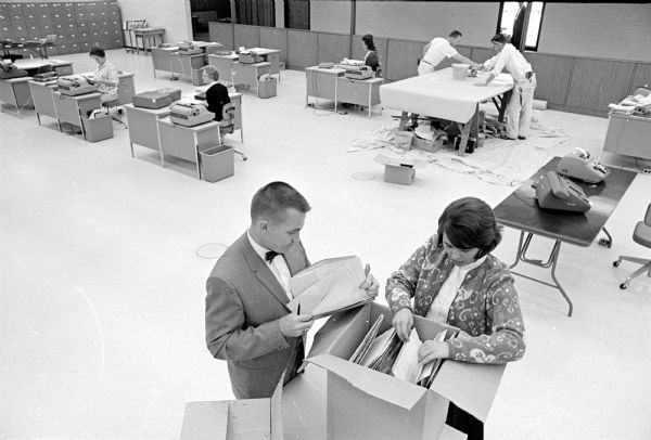 Elevated view of the interior of Graber Co., producer of drapery hardware, a new plant off Hwy 12 at the northern edge of Middleton. Paperhangers are pictured in the background, while employees in the accounting department (Vern Weisensel, office manager and Pat Heiberg) are pulling files from cartons.