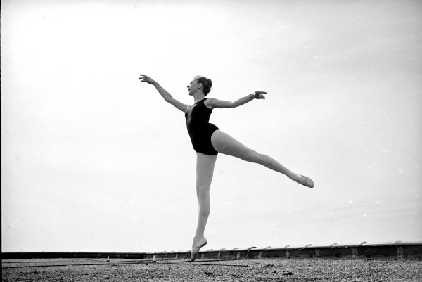 Mimi Pansley (?), of McFarland, performing a temps levé in arabesque, an elevation from one foot into the air from the arabesque position, to show the similarity to a basketball player battling for a rebound.