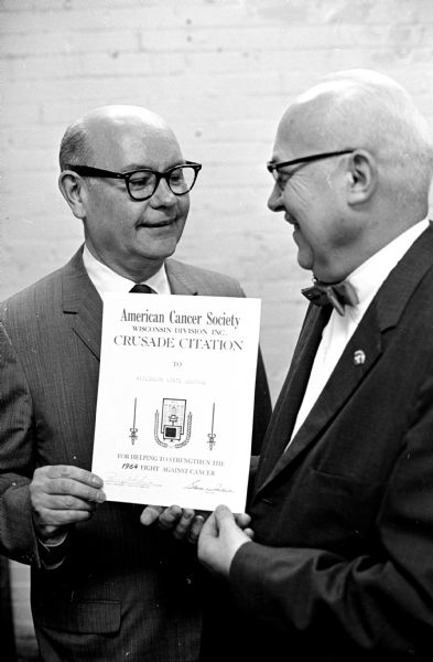 The Wisconsin State Journal received the American Cancer Society's Crusade Citation "for helping to strengthen the 1964 fight against cancer." Richard C. Wilson, right, presented the citation to Lawrence H. Fitzpatrick, managing editor of the Wisconsin State Journal, for the "continuing educational program carried in the newspaper to enable people to recognize the danger signals of cancer and obtain early treatment." Wilson is a member of the board of the Dane County unit of the Wisconsin Division of the American Cancer Society.