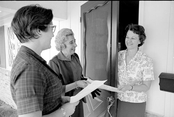 Nancy Rude (left), president of the University League-Newcomers, and Kathryn Stauffer, president of the University League, are shown presenting the calendars of their organizations to Alduth Fleming, wife of the university's first provost of the Madison campus.