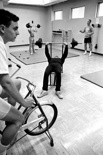 In one of a series of photographs showing the luxurious features of private dormitories on campus, Harry Himmelstein, Kansas City, Missouri; Barry Stagman, Winnetka, Illinois; James Miller Jr., St Croix Falls; and Robert Aubre, Union Illinois are shown exercising at the gymnasium at Wisconsin Hall, 126 Langdon Street.