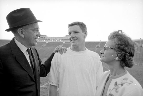 The original caption states: "Mr. and Mrs. William Frasier, Rhinelander, chat with their son, Larry, defensive halfback, at practice."