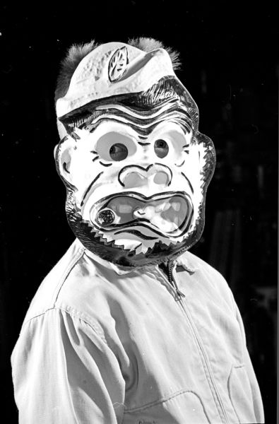 Portrait of Gene Hagen wearing a mask of a open-mouthed gorilla.