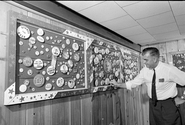 Ralph Callies pointing to one of the thousands of political buttons in his collection. He is a member of the American Political Items Collectors.