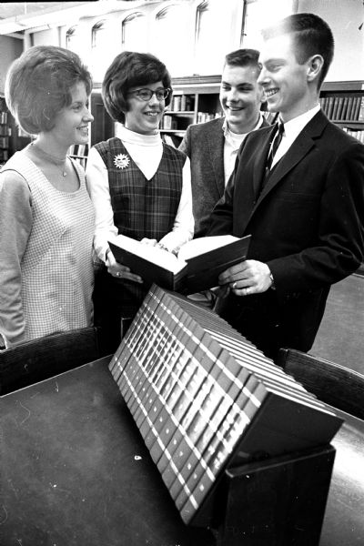 Four East High School students looking over a set of World Book encyclopedias they won by submitting questions to the Wisconsin State Journal's Uncle Ray column. The four, students in teacher Ralph Gibson's U.S. History classes, are, left to right: Kristine Natvig, Linda Roller, Stephen Suhr, and Gary Plath. The questions were about the nature of the U.S. presidency.