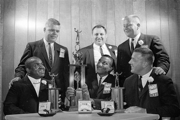 Key men and players for the Madison Mustangs football team at their first annual banquet. Sitting in the center is quarterback Arnie Motl, who is admiring the trophy for most valuable player. Also seated are the newly-elected co-captains Joe Heatly, left, and Jim Currie, right. Standing are, left to right: president John Fox, general manager Joe Cerniglia, and coach Wendell (Windy) Gulseth.