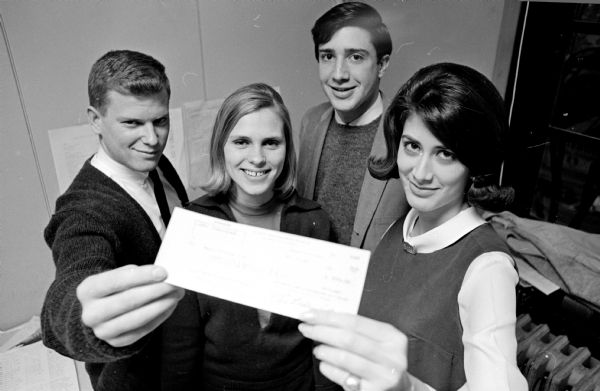 Four U.W. students shown with the check presented to the Wisconsin State Journal's Christmas Empty Stocking Club fund. It was the result of proceeds from Humorolgy, the annual fraternity-sorority benefit show.  Left to right: Gary Cole, Interfraternity Assn. president; Ann Reinbe, Panhellenic Assn. president; Elliot Abelson, general chairman of Humorology; and Marilyn Katz, Panhellenic public relations chairman.