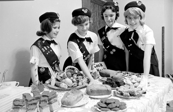 Members of Blessed Sacrament Cadette Girl Scout troop shown preparing to serve pastries at a "tasting tea" at the school.  They baked the food themselves and will serve it to visitors and sell breads, fudge, cookies, cakes and donuts. Left to right:  Linda Murphy, Kathy McDonald, Mary Wallace, and Ginger Ball.