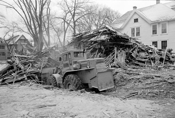 A bulldozer demolishing five homes in the four hundred block of West Washington Avenue to make room for a six-story office building to be the Wisconsin headquarters of the American Automobile Association.
