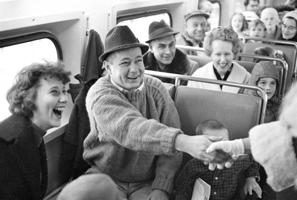 The Santa Express Train went from Madison to Stoughton and back, with 6,000 children. This view shows some of the enthusiastic parents going along. The man in the foreground is shown shaking Santa's hand.
