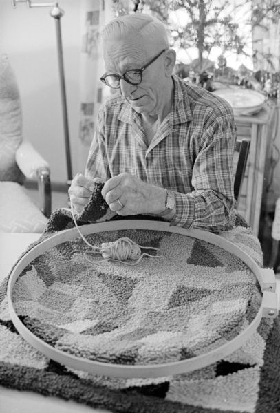 Henry Hinze, age 83, working on a hooked rug to give to his children. He has been hooking rugs since he had a heart attack ten years ago.