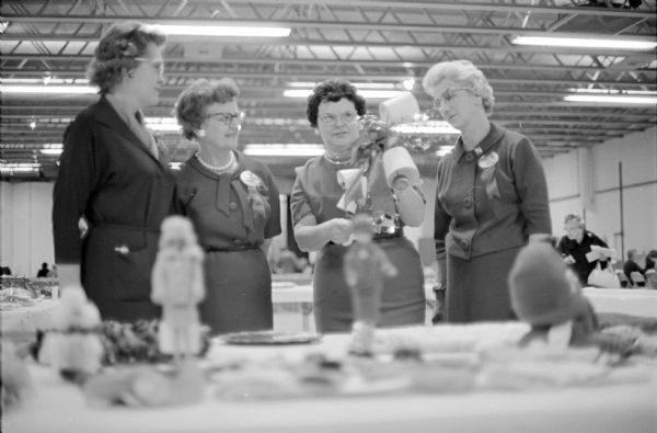 Members of participating clubs in the Dane County Homemakers displayed Christmas ideas and decorations at the annual tea. Mrs. Fredric Chase, Mrs. James Kreps, Mrs. Alfred Henschel and Mrs. Reuben Bredeson, all members of the DeForest Hostess Club, are looking at the displays.