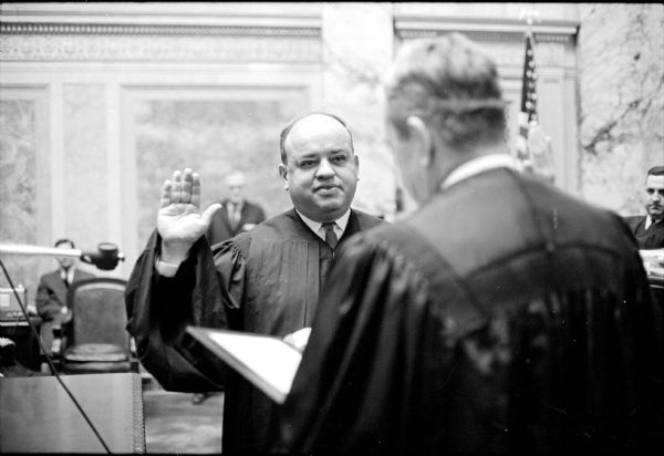 Justice Horace Wilkie taking his oath of office from Justice Nathan Hefferman in the Supreme Court Chamber of the Capitol Building. He is being sworn in to a full 10-year-term on the State Supreme Court.