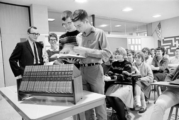 David Bednarek, left, education writer for the Wisconsin State Journal, presenting a set of World Book encyclopedia to Schenk Junior High school for submitting questions to the Uncle Ray column in the paper. The teacher standing next to David is Suzann Reichley, and the two students are Mike Macaulay and Mike McGinnis.