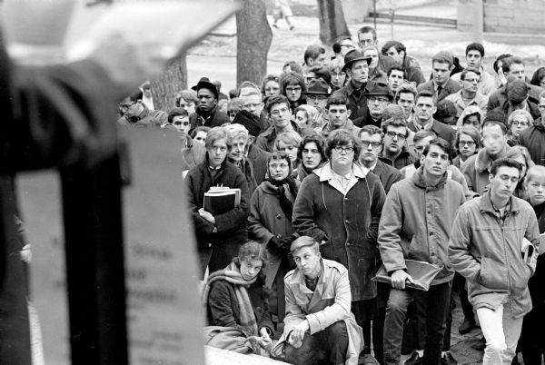 A crowd of about 200 people are gathering in front of the U.W. Memorial Union at a U.W. sponsored rally in support of the United Nations. The accompanying article referred to various speakers, including: Thomas Fairchild, Donald McNeil, Thomas Tinkham, John McGrath, and Nat Sample.