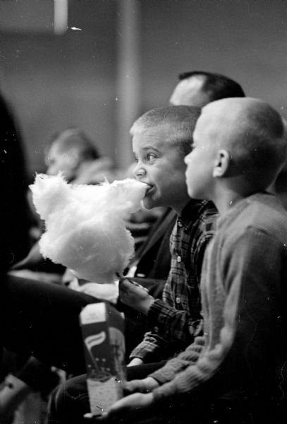 A young boy enjoying the Zor Temple-William Kay Shrine circus at the Dane County fairgrounds arena while eating cotton candy.