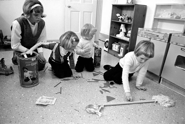 Baby sitter Christine Steiner, 11, at left encouraging her three little "clients" to assist her in straightening up their playroom.
Obediently responding are, left to right: Suzi, 4; Kerry Jean, 3; and Cheri, 5, daughters of Mr. and Mrs. Michael Welch, Sun Prairie.