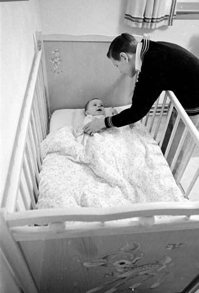 Trained baby sitter Dan Unmuth, 13, is shown straightening out the bedding of his lively charge, Danny Groh, 15 months.