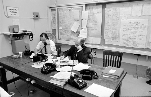 Governor Warren Knowles' Command Post, located in the Capitol, was called into action after tornadoes struck southern Wisconsin. It serves as the disaster communications center for the state. Pictured are, left to right, Bob Curley, public information officer for Civil Defense, and Colonel John Roach, deputy adjutant general of the Wisconsin Army National Guard.