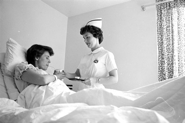 Donna Osness giving medication to Louise Yeazel, a patient at Madison General Hospital. One of a series of images about Donna, a mother of five children, who is participating in a new Madison General School of Nursing program for married women.